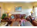 Cozy living room featuring a brown leather sofa, tropical-themed decor, and ample natural light at 2724 Via Murano # 639, Clearwater, FL 33764