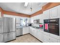 Well-lit kitchen featuring white cabinets, stainless steel appliances, and tiled flooring at 3119 Roberta St, Largo, FL 33771