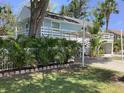 Charming light blue home with white trim, elevated deck and lush landscaping, offering a serene tropical feel at 401 Pennsylvania Ave, Crystal Beach, FL 34681