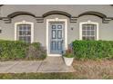 Close-up of a stylish front door with decorative trim, flanked by windows and manicured hedges at 5396 Berrien Ave, Spring Hill, FL 34608