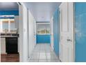 Hallway view with white tile flooring and blue painted walls with access to the kitchen and several closets at 638 La Jolla Ave, Sun City Center, FL 33573