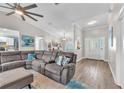 Bright living room with vaulted ceiling, gray sectional sofa, hardwood flooring, and an open layout at 832 Birdie Way, Apollo Beach, FL 33572