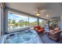 Enclosed patio featuring a relaxing hot tub, comfortable seating, and a view of a serene lake at 832 Birdie Way, Apollo Beach, FL 33572