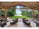 Relaxing outdoor seating area under a tiki hut with a view of the backyard and lake at 8903 Donna Lu Dr, Odessa, FL 33556