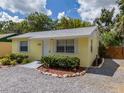 Attractive yellow home with neat landscaping, a gravel driveway, and a welcoming front door at 932 W Wheeler Rd, Brandon, FL 33510