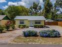 Quaint yellow home with a gravel driveway, complemented by vibrant landscaping and a classic white door at 932 W Wheeler Rd, Brandon, FL 33510