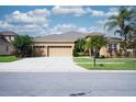 Charming single-story home boasts a well-manicured lawn, a three-car garage, and mature palm trees at 10513 Palm Cove Ave, Tampa, FL 33647