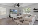 Bright living room featuring white leather sectional, modern fan, and large windows at 10823 Trailing Vine Dr, Tampa, FL 33610