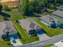 Aerial view of a well-maintained home with a paved driveway, green lawn, and mature trees in a residential neighborhood at 12492 Eastpointe Dr, Dade City, FL 33525
