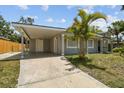 View of the home's carport and driveway, accentuated by a vibrant palm tree and modern gray paint at 1905 E Broad St, Tampa, FL 33610