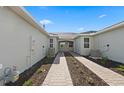 Exterior side view of the home showcasing pathway, lawn, and architectural details at 27136 Capri Shores Cir, Englewood, FL 34223