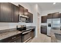 Well-equipped kitchen with stainless steel appliances, dark cabinets, and granite countertops at 3186 Oyster Cove St, Wimauma, FL 33598