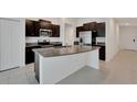 Modern kitchen with a large island, granite countertops, stainless steel appliances, and dark cabinetry at 3186 Oyster Cove St, Wimauma, FL 33598
