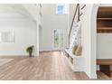Bright, open foyer with a glass-paneled front door and wood-look floors, plus built-in bench and storage under the stairs at 4383 Ortona Ln, Wesley Chapel, FL 33543