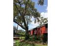 Exterior view of a red brick building with balconies, surrounded by lush greenery and mature trees at 8220 12Th N Way # H, St Petersburg, FL 33702