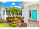 Close up of home's entrance highlighting the turquoise door, surrounding plants and brick pillar at 859 Harbor Hill Dr, Safety Harbor, FL 34695