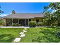 Inviting home exterior with a well-kept lawn and stepping stone pathway leading to a charming screened porch at 859 Patterson Dr, Sarasota, FL 34234