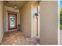 A cozy front porch with brick flooring, an elegant front door with glass, and decorative hanging lights at 1242 Windy Bay Shl, Tarpon Springs, FL 34689