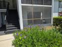 Exterior view of the building with a staircase, screened in porch, and beautiful landscaping at 1281 Pine Ridge E Cir # B1, Tarpon Springs, FL 34688