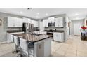 Bright kitchen featuring white cabinets, stainless steel appliances, granite countertops, and a center island with bar stools at 12835 Wildflower Meadow Dr, Riverview, FL 33579
