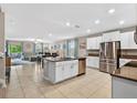 Open kitchen layout with white cabinets, stainless steel appliances, and a view of the dining and living areas at 12835 Wildflower Meadow Dr, Riverview, FL 33579