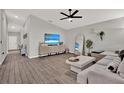 Bright living room with a ceiling fan, TV, light gray walls, wood-look flooring, and stylish furniture at 13111 Fruitville Way, Riverview, FL 33579