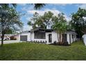 This home features a white exterior, dark trim, manicured landscaping, and an attached garage, offering both curb appeal at 1506 Winding W Way, Clearwater, FL 33764