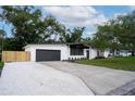 Modern single-story home with a gray garage door, fresh white exterior paint, and a concrete driveway with gravel at 1506 Winding W Way, Clearwater, FL 33764