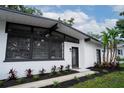 The exterior features a mix of modern design with large windows and brick, enhanced by lush landscaping and mature palms at 1506 Winding W Way, Clearwater, FL 33764