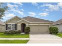 Welcoming single-story home featuring a well-manicured lawn, an attached two-car garage, and a charming covered entryway at 15406 Gopher Trop Pl, Sun City Center, FL 33573