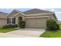 Close-up of the two-car garage with a driveway and well-kept bushes at 15406 Gopher Trop Pl, Sun City Center, FL 33573