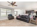 Bright and airy living room featuring carpet, ceiling fan, and open layout connecting to the kitchen area at 15406 Gopher Trop Pl, Sun City Center, FL 33573