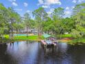 Aerial view showcasing the property with a pool, boat house, lake access, and lush landscaping at 16205 Sentry Woods Ct, Odessa, FL 33556