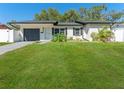 Lovely single-story home with manicured lawn, black shutters and garage door, plus mature landscaping at 4111 Whiting Se Dr, St Petersburg, FL 33705