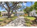 Inviting home featuring lush green lawns, a concrete driveway, and mature trees providing ample shade on a sunny day at 4870 47Th N Ave, St Petersburg, FL 33714