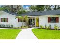 Charming home featuring a yellow front door, red shutters, meticulous landscaping and a walkway to the entrance at 6921 N 16Th St, Tampa, FL 33610