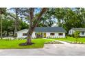 Charming single-story home with a manicured lawn, mature trees and bright yellow front door at 6921 N 16Th St, Tampa, FL 33610