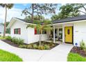 Beautifully landscaped front exterior with a bright yellow door and charming front porch at 6921 N 16Th St, Tampa, FL 33610