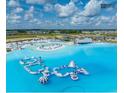 Wide aerial shot featuring the lagoon with a floating obstacle course and inflatable slides at 10747 Laxer Cay Loop, San Antonio, FL 33576