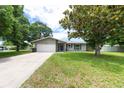 Traditional-style home featuring a two-car garage, manicured lawn, and a welcoming entrance amidst mature trees at 1461 S Hillcrest Ave, Clearwater, FL 33756