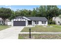 Charming home featuring black trim, a gray garage door, and a well-manicured front lawn at 15012 Winterwind Dr, Tampa, FL 33624