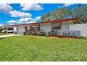 Single story house with red trim and planted garden in front of the house and attached garage at 1809 Chinaberry Dr, Oldsmar, FL 34677