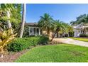 Landscaped front yard featuring tropical foliage and a patterned driveway leading up to a charming single-story home at 200 Lamara Ne Way, St Petersburg, FL 33704