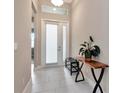 Bright and airy entryway with white tile flooring, transom window, and stylish console table at 3060 Mountain Spruce Ter, Wesley Chapel, FL 33543