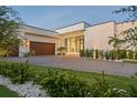 Modern home with beautiful landscaping, a paver driveway, and wood-look garage door at 501 Barcelona Dr, Tierra Verde, FL 33715