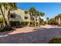Scenic view of the condo building featuring a brick-paved parking area and lush palm trees at 505 Sandy Hook Rd # 505, Treasure Island, FL 33706