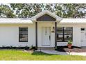 Inviting front entrance with a white door, dark pillars, and landscaped flower beds at 706 E Gate Dr, Safety Harbor, FL 34695