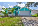 Charming home featuring a teal exterior, arched windows, well-maintained lawn, and a two-car garage at 10430 Crestfield Dr, Riverview, FL 33569