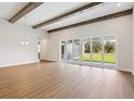 Bright living room featuring wood-look flooring, decorative ceiling beams, and sliding glass doors leading to the outdoors at 14523 Swiss Bridge Dr, Lithia, FL 33547