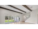 Living room with wood beams, sliding glass doors to backyard and white staircase at 14531 Swiss Bridge Dr, Lithia, FL 33547
